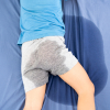 Rückenansicht eines Vorschulkindes, das mit nasser Hose im Bett liegt