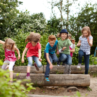 Kinder springen über Baumstamm